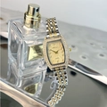Detail of tonneau emerald quartz watch with crystal bezel on a silver reflective tray - Two-tone Gold Dial