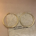 Detail of large gold hoop earrings with polished metal finish on warm textured background - Gold Large Shiny Style (55#)