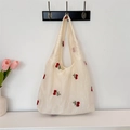 Detail der zarten roten Kirscherstickerei auf cremefarbenem Canvas-Tote-Bag mit Blumen - Cremeweiß Bestickte Kirsche