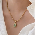 Collana vintage a catena piatta con ciondolo a goccia verde indossata da una modella - Goccia d'acqua Verde / Catena d'oro