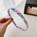 Flat acetate headband featuring a purple and green tie-dye pattern held by hand - Purple & Green