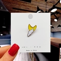 Detail of cute yellow moon and white cloud enamel pin held by a hand in a cafe setting - 10*Cloud and Moon Pin