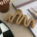Matbruine golvende haarklem in een minimalistisch ontwerp op een beige achtergrond - Gematteerde golfstijl / camel