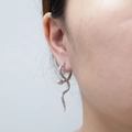 Elegantes pendientes de serpiente plateados con textura de escamas usados por una modelo - Pendientes de Serpiente Pequeña Color Acero