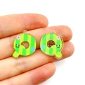 Macro shot of striped acrylic Q-letter charms with glitter finish on fingertips - Letter Q
