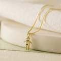 Macro shot of gold boy-shaped pendant necklace with cubic zirconia on a white tray - November Olive Green