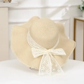 Detail of beige straw hat with large wavy brim and elegant white lace floral bow - Plum Wave Beige