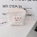 Close-up of white polka dot cotton makeup pouch with embroidered colorful logo and zipper - Wrinkled Polka Dot White