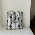 Close-up of ethnic floral embroidery and fabric texture on a white canvas tote bag - White with Navy Embroidery