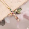 Dettaglio del ciondolo a croce dorata con zirconi colorati su superficie in pietra - 4# Multicolore