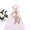 Golden letter N keychain with sparkling crystals, crown detail, and daisy background - Letter N / Gold