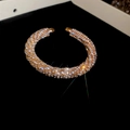 Primer plano de brazalete abierto en oro rosa con incrustaciones de strass brillante - Dorado