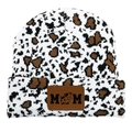 Detail der Strickmütze mit Kuhmuster und Lederaufnäher mit MOM-Text und Kuh-Symbol - MOM Stil / Kleines Leopard/Schwarz Braun Weiß