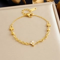 Bracelet en acier inoxydable doré avec trèfles et zircons sur coussin de satin beige - Bracelet Doré (B1939)
