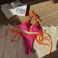 Close-up of pink ribbed bikini set with orange contrast ties and metallic ring hardware - Rose Red
