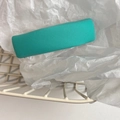 Detail shot of a turquoise fabric-covered rectangular hair clip on soft white paper - Fresh Green