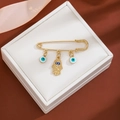 Detailed view of gold Hamsa hand and blue evil eye charms in a premium white jewelry gift box - Enamel Hamsa Style (Z232-2)