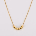 Gros plan d'un collier doré minimaliste avec six perles carrées sur une chaîne fine - Or