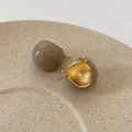 Vue macro de boucles d'oreilles en émail thé au lait avec finition dorée sur plateau - Boucles d'Oreilles Boules Émail Rétro - Gris
