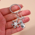 Vintage Christmas snowman and snowflake keychain held by hand on pink background - Snowflake/Snowman