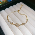 Dettaglio macro di bracciale dorato con fiori e zirconi in scatola di velluto - Oro-Fiore