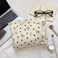 Close-up of corduroy makeup bag with brown heart patterns on a desk workspace - Off-white