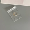 Detail of a golden open ring stored in a thick transparent EVA anti-oxidation jewelry pouch - 50 Silk Transparent Zipper Bag / 6x8cm