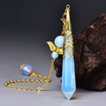 Detailed shot of opal crystal pendulum with golden filigree and wing accents on wood - Gold Opalite