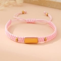 Macro shot of pink braided bracelet with a polished gold metal plate and adjustable closure - Pink (Gold Plate)