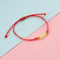 Detalle de pulsera de cordón trenzado rojo con cierre ajustable y barra de metal dorado - Cuerda Roja Dorada