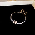 Detailed macro of gold adjustable bracelet with rectangular pink zircon and white stones - Gold-Pink