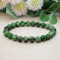 Detailed view of green natural stone beads bracelet on a rustic wood background - Unakite