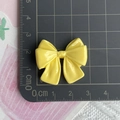 Detailed scale view of a yellow resin bow charm measuring 3cm by 2.5cm on a cutting mat - Yellow
