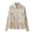 Macro detail of champagne satin shirt featuring delicate floral embroidery and silk texture - XS / Tops / Apricot
