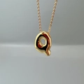 Macro shot of polished gold letter Q pendant necklace with smooth metallic texture - Letter Q Single Pendant
