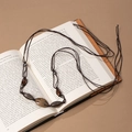 Close-up of bohemian hand-woven waist chain with vintage metal beads on a book - Dark Brown Rope Antique Silver Bead (X451-9)
