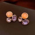 Detailed macro view of gold-tone triangle earrings with orange, pink, and purple crystals - Orange Cat's Eye Cluster Geometric Style
