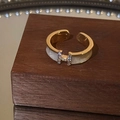 Macro shot of gold plated H-letter open ring with zircon stones on dark wood stand - 4 Gold Rings