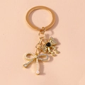 Dettaglio portachiavi dorato con fiocchi, strass scintillanti, perle e un cuore nero - Fiocco di Perle