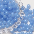 Close-up of 8mm light blue frosted glass beads scattered around a decorative bowl - Blue and Purple