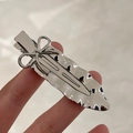 Silver bow hairpin with zircon micro-inlay and irregular leaf design in hand - Uneven Metal Smooth Bowknot Clip