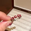 Handheld view of a silver floral ring with vibrant red enamel petals in a jewelry box - Enamel Flower Ring