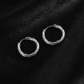 Macro detail of silver twisted hoop earrings with textured finish on black silk - Spiral Geometric / Steel