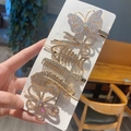 Detalle de 6 horquillas doradas con pedrería en forma de tijera, espina de pescado y pluma - Juego de 6 Piezas de Mariposa
