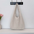 Detailed view of beige pleated fabric shoulder bag with brand label and soft texture - Beige