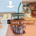 Bamboo-shaped glass coffee cup with brown sleeve and green straw in a hand-held shot - Short Cup with Coffee Fabric Sleeve (Only You)