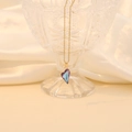 Macro detail of a heart-shaped purple crystal pendant with a gold chain on silk - Light Purple