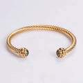 Goldenes gedrehtes Kabelarmband mit grünen Steinakzenten in klassischem Manschettenstil - Gold mit grünem Zirkon