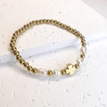 Detail of gold beads, baroque pearls and a clover charm on an elastic bracelet - Four-Leaf Clover / Gold