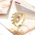 Detalle macro de anillo de ojo dorado con esmalte rojo y circonitas sobre papel de estilo retro - Ojo Rojo